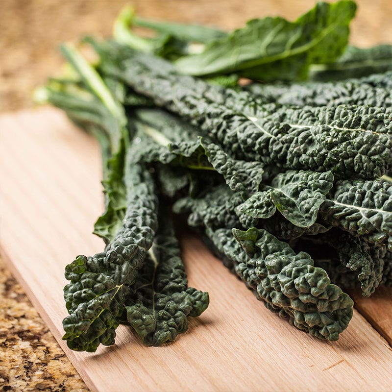 Fresh picked kale lays on a cutting board on a marble countertop